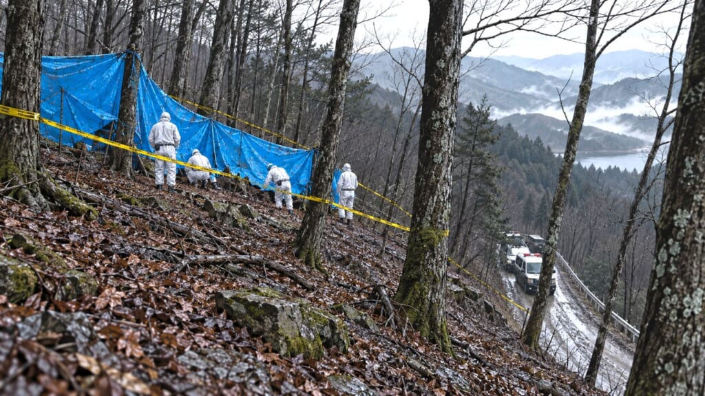 曇天の山中、ブルーシートと規制テープが張られた現場